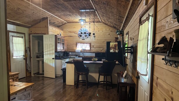 A cozy cabin interior with a wooden interior, a kitchen area with a sink and counter, and a dining area with a bench and chairs. - Quiet cabin in the hills close to the trails and other outdoor activities.<br> (Genoa)