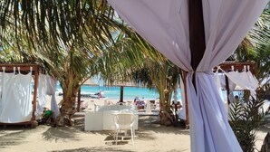 A beachside outdoor area with a covered seating area, palm trees, and a view of the ocean. - Appartement Praia Center (PRAIA)