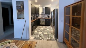 A modern kitchen with a patterned floor, wooden cabinets, and a built-in oven. - Appartement Praia Center (PRAIA)