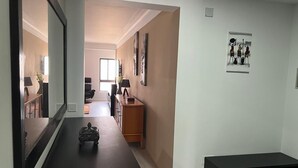 A hallway with a dark wooden bench, a small decorative item, and a framed artwork on the wall. - Appartement Praia Center (PRAIA)