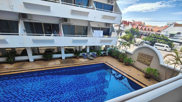 A rooftop swimming pool with a tiled floor, surrounded by potted plants and a seating area. - Big Appartment 101 80 Sqm (Pattaya)
