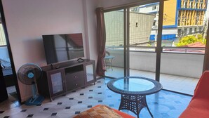 A room with a TV, a fan, a glass table, and a sofa. - Big Appartment 101 80 Sqm (Pattaya)