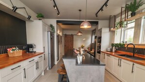 A modern kitchen with a central island, wooden countertops, and bar stools.