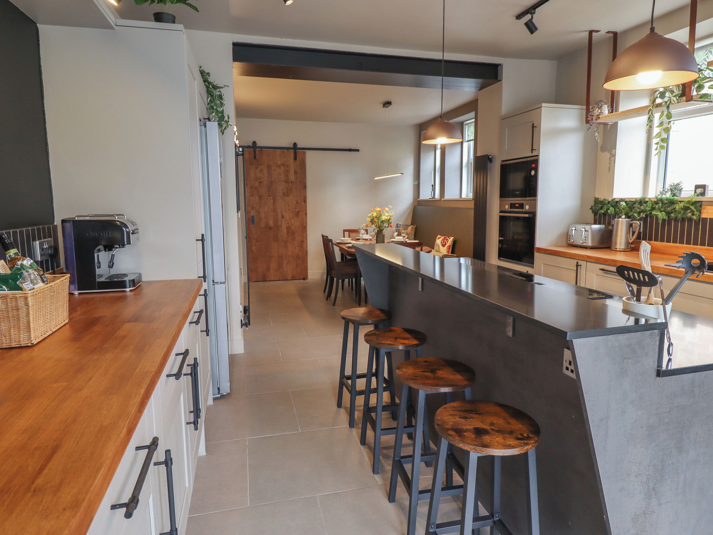 Una cocina moderna con una isla central, taburetes de bar, una cafetera y un tostador.