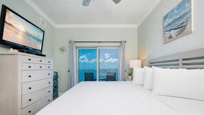 Hotelkamer met een bed, een kaptafel, een televisie, een balkon met uitzicht en een schilderij aan de muur.