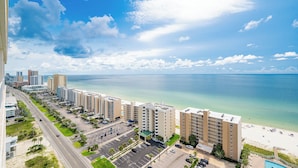 Een hotel aan de kust met meerdere gebouwen, een parkeerplaats en uitzicht op het strand.