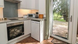 Eine kleine Küche mit Mikrowelle, Toaster und Schneidebrett aus Holz.