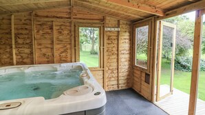 Eine Holzhütte mit Whirlpool, Holzwänden und großen Fenstern.