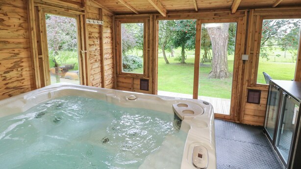 Eine Holzjagdhaus mit Whirlpool, großen Fenstern und Gartenblick.