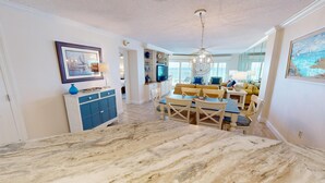 A spacious living area with a marble floor, a dining table, and a television in the background. - Inlet Reef 204 is a stunning 2 BR Gulf front - Recently Renovated (Destin)