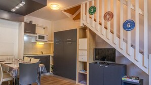 Eine kompakte Küche mit Essbereich, einem Fernseher und einer Treppe mit nummerierten Stufen.