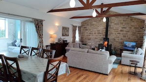 Ein gemütliches Wohnzimmer mit Steinwand, Kamin und Fernseher.
