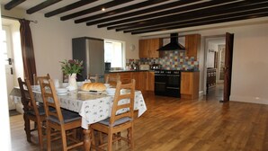 A dining area with a wooden table and chairs, a vase with flowers, and a loaf of bread. - Jacobswell House – Dog‑Friendly 3‑Bedroom Cottage with Field Views & Cycle Storage (Cramlington)