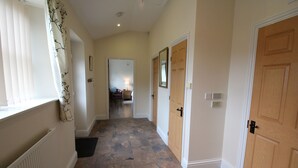 A hallway with stone flooring, wooden doors, and a radiator on the left. - Swallow Cottage - Accessible cottage with wetroom, dog friendly, working farm (Cramlington)