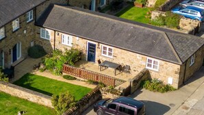 A stone house with a fenced patio, a car parked in front, and a small garden. - Swallow Cottage - Accessible cottage with wetroom, dog friendly, working farm (Cramlington)