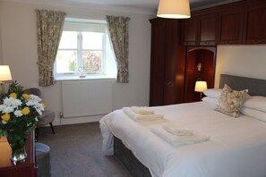 Relax in a cozy space with a large bed, bedside table, and elegant vase of flowers.