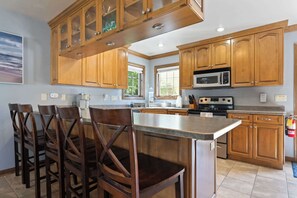 A kitchen with wooden cabinets, a microwave, a stove, and a dining area with chairs. - Retreat at Sunshine Creek, Downtown Fish Creek (Fish Creek)