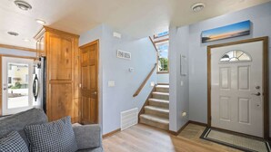 Ein Flur mit einer Holztür, einer Treppe, einem Sofa und einem Schild an der Wand.