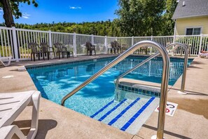 A swimming pool with a metal ladder, lounge chairs, and a white fence. - Retreat at Sunshine Creek, Downtown Fish Creek (Fish Creek)