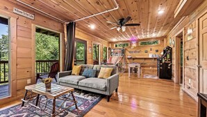 L’intérieur d’une cabane avec un plafond en bois, un canapé, une table basse, un baby-foot et une enseigne indiquant « Game Cave ».