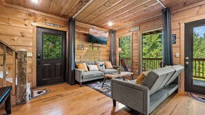 L’intérieur chaleureux d’un chalet, avec un revêtement mural en bois, un canapé, un fauteuil et une petite table.
