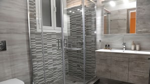 A modern bathroom with a glass-enclosed shower, a white toilet, and a vanity with a mirror.