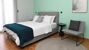 A modern bedroom with a bed, a side table, and a chair.