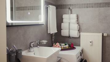 A bathroom with a sink, mirror, towel rack, and a washing machine.