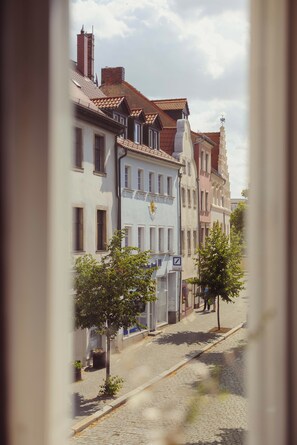 Une rue pavée bordée de bâtiments historiques, un ciel dégagé et quelques piétons.