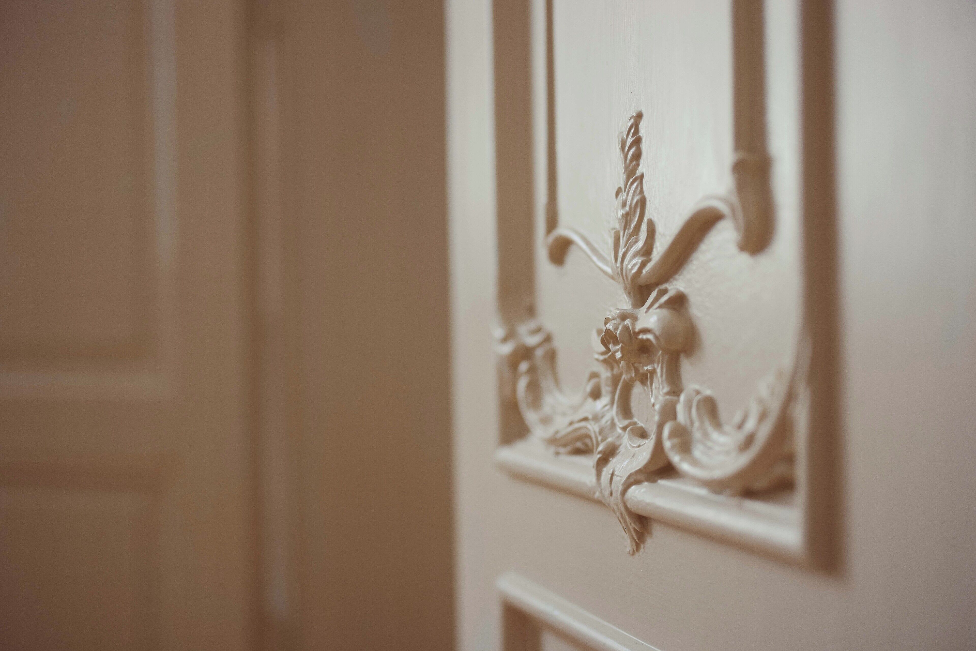 A close-up of a white door with ornate carvings.