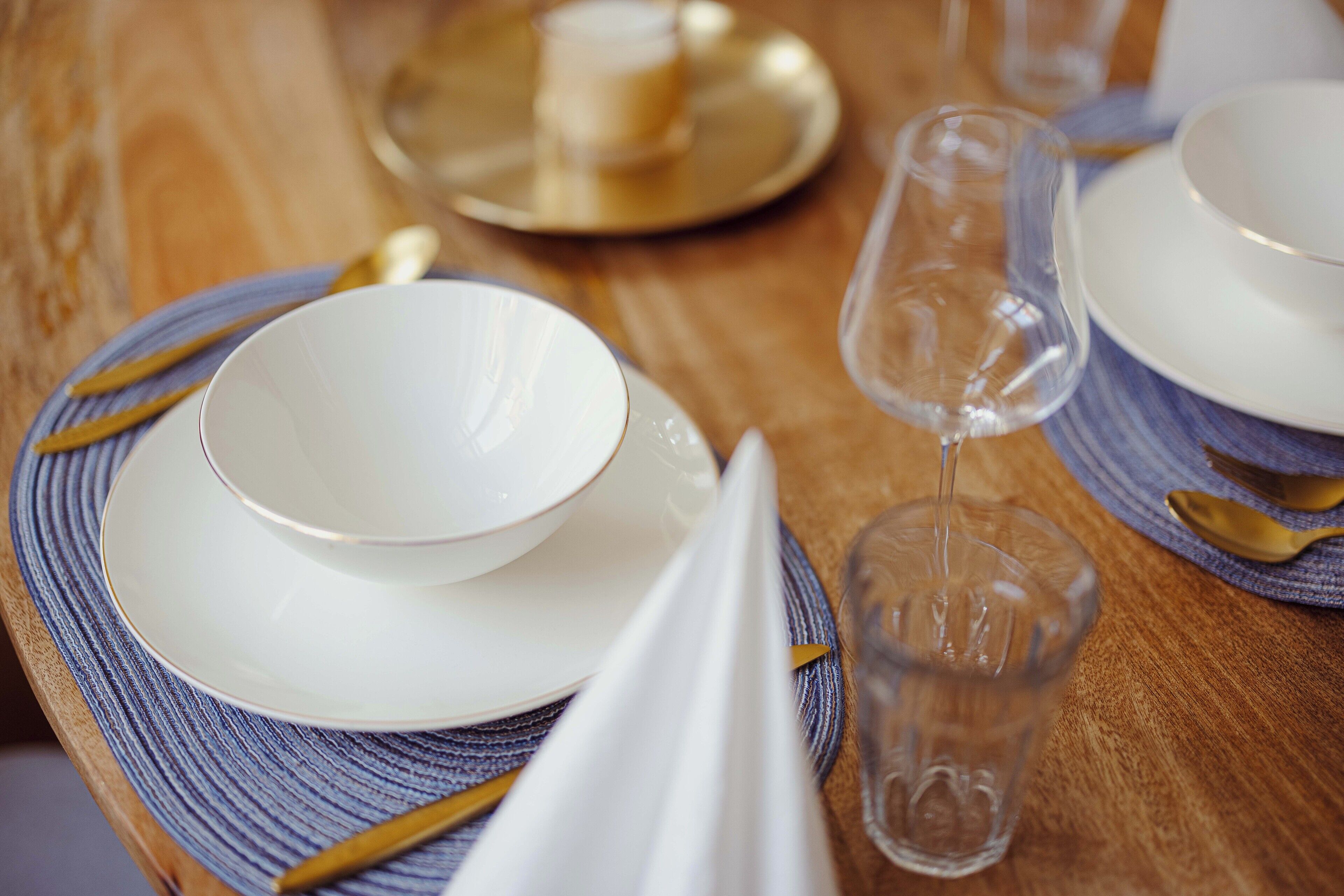 A table set with white plates, a clear glass, and a gold spoon.