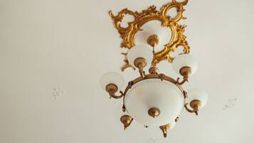 Un lampadario con più bracci e paralumi in vetro, fissato a una parete con una cornice dorata decorativa.