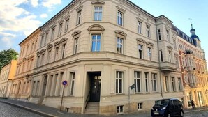 Een historisch gebouw met een hoopingang, grote ramen en een koepel aan de rechterkant.