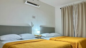 A hotel room with two beds, a nightstand with a lamp, an air conditioning unit, and a curtain.