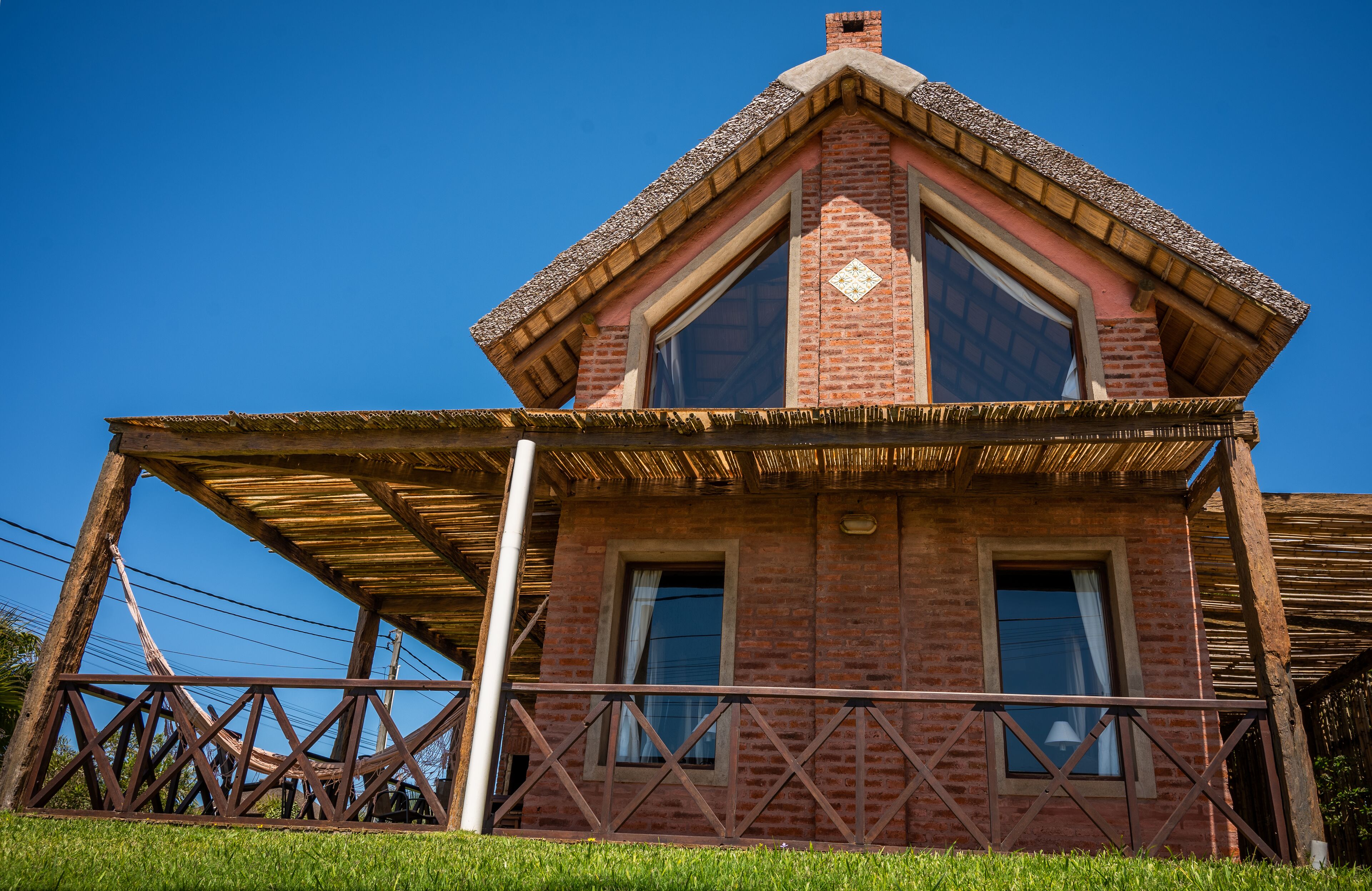 A brick building with a gabled roof and a wooden balcony.