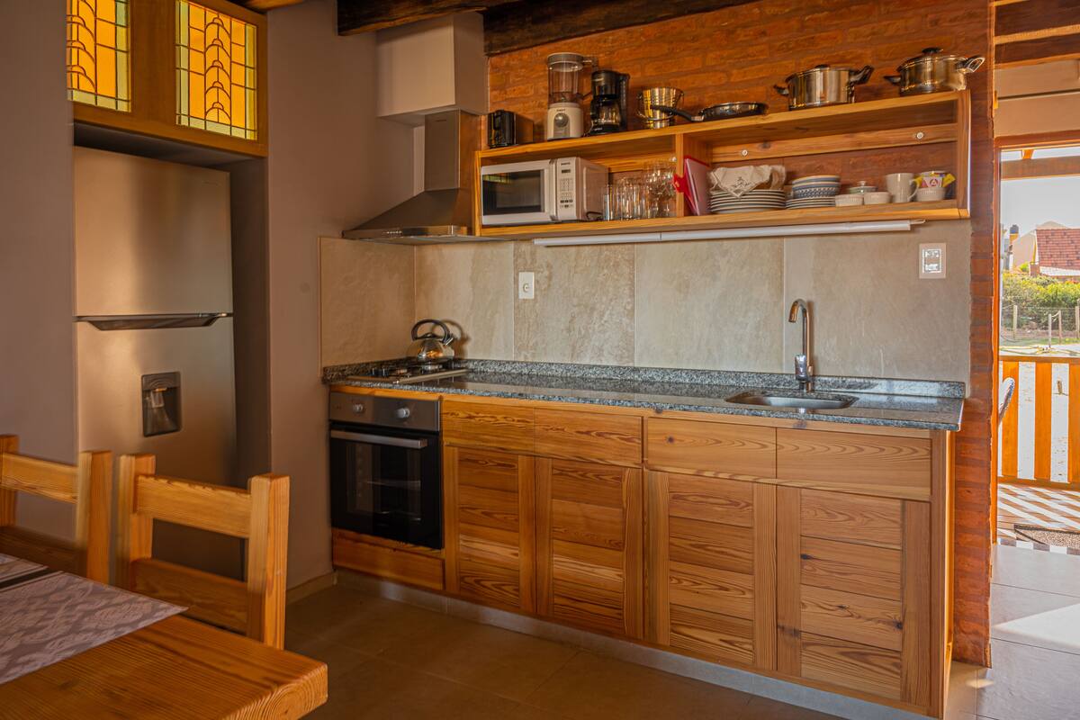 A kitchen with wooden cabinets, a built-in oven, a microwave, and a sink.