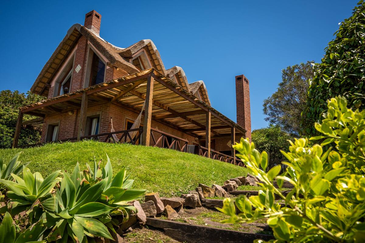 A large, rustic house with a steeply pitched roof and a brick chimney.