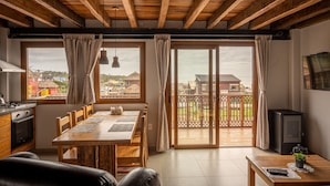 A cozy living room with a wooden ceiling, a dining table, and a view of a balcony with a railing. - Muelles del Diablo Tranquilo (Punta del Diablo)