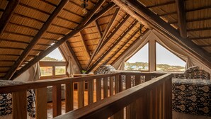 An attic bedroom with a sloped roof, wooden beams, and large windows offering a view of the landscape. - Muelles del Diablo Tranquilo (Punta del Diablo)