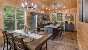 L’intérieur d’une cabane en bois comprend un coin repas, une cuisine et de grandes fenêtres.