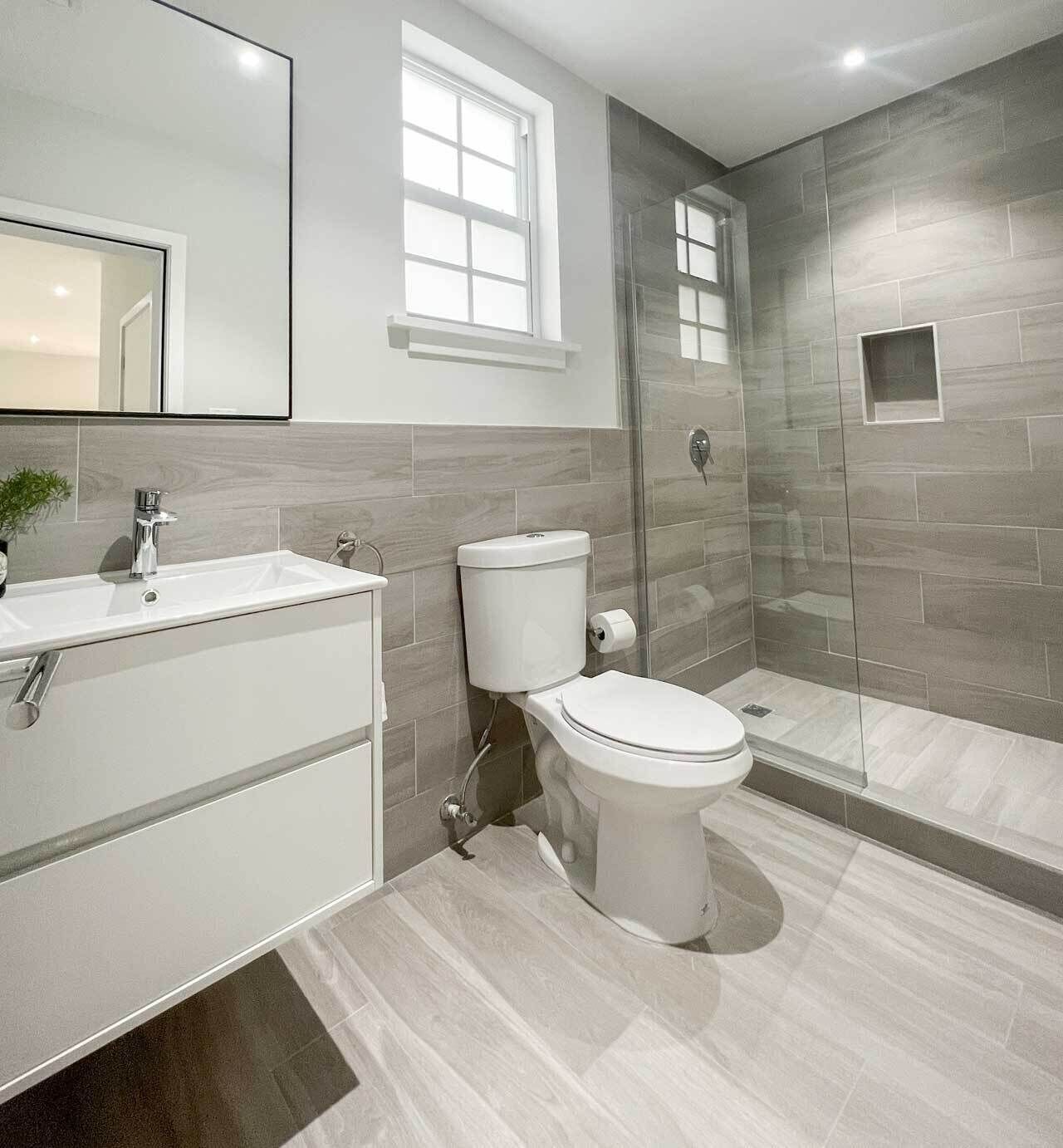 A modern bathroom with a white sink, toilet, and shower.