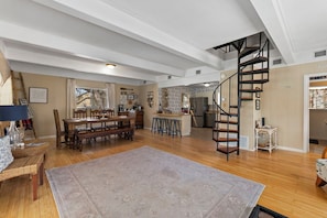 Ein geräumiger Wohnbereich mit Esstisch, Treppe und einer Küche im Hintergrund.
