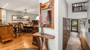 A spacious kitchen with wooden cabinetry, a dining area with a large table and chairs, and a hallway leading to a door.