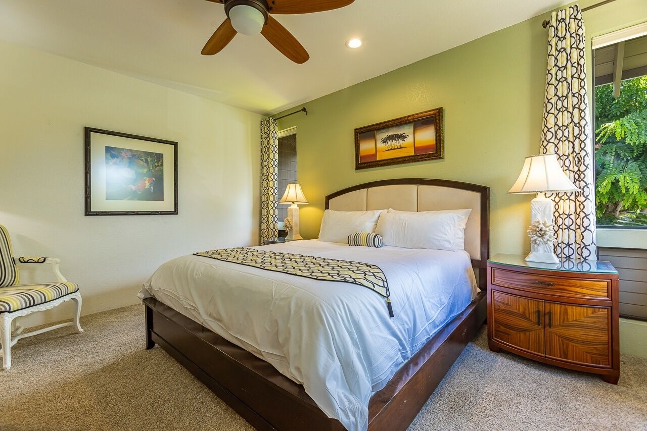 A bedroom with a bed, a chair, a nightstand, and a ceiling fan.