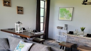 Una sala de estar moderna con un sofá gris, una mesa de comedor de madera y una zona de cocina con un mapa en la pared.