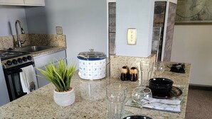Una cocina con encimeras de granito, estufa, lavabo y comedor con mesa para dos.