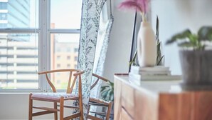 A room with a wooden chair, a mirror, a dresser, and a window with a view of buildings. - Luxe Downtown Penthouse! In the Heart of City w/Parking!! (Raleigh)