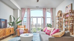 A modern living room with a sofa, armchair, coffee table, and a bookshelf. - Luxe Downtown Penthouse! In the Heart of City w/Parking!! (Raleigh)