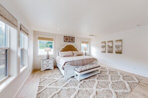 Classic bedroom with a large bed, tufted headboard, and matching bench, complemented by patterned rug and framed artwork.