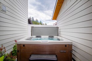 Relax in a serene outdoor setting with a hot tub and lush greenery.